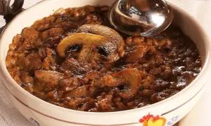 Una ciotola decorata con una ricca zuppa di farro e funghi, pronta per essere servita con un mestolo.
