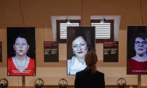 Eine Frau betrachtet drei Bildschirme mit Porträts von Frauen. Die Installation thematisiert die **Vergangenheit gegenwart** und individuelle Interviews aus Ost- und West-Berlin.