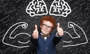 Chłopiec w okularach i garniturze pokazuje kciuki do góry na tle tablicy z wzorami matematycznymi i rysunkami mózgu i mięśni.