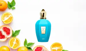 Błękitna butelka perfum Sospiro Erba Pura otoczona cytrusami i liśćmi.