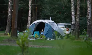 Namiot i samochód w lesie, idealne miejsce na ferie 2026 śląskie. Girlanda świetlna dodaje uroku.