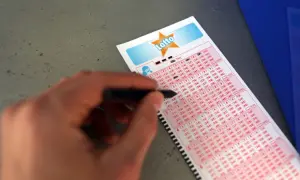 Ręka zaznacza liczby na kuponie Lotto. Analiza historycznych wyników pod kątem najrzadziej padających liczb.
