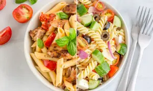 Dos deliciosas ensaladas de pasta: una con pollo a la parrilla y tomates, la otra con verduras frescas y queso.