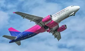 Samolot Wizzair z różowo-niebieskim malowaniem wznosi się na tle błękitnego nieba. Może to być symbol nadziei na nowy, odwołany lot Wizzair.