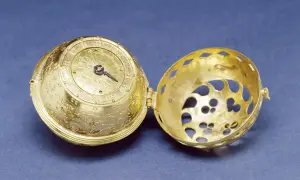 Esfera dorada ornamentada de un primer reloj mecánico, abierta para mostrar su intrincado interior.
