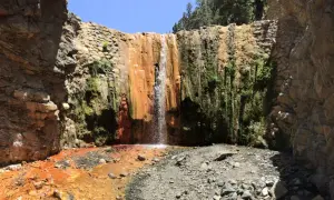 Cascada rojiza y verde en un cañón rocoso, ideal para senderismo en Palma de Mallorca.