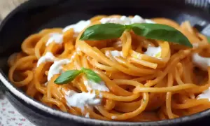 Spaghetti med krämig tomatsås och burrata, toppad med färsk basilika. En härlig pasta burrata-rätt.