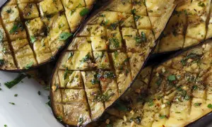 Gegrillte Auberginenhälften, mit Kräutern und Knoblauch gewürzt, bereit zum Servieren. Ein köstliches Gericht, das die Aromen des Ofens einfängt.