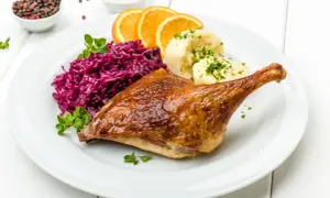 Pieczona kaczka z purée, czerwoną kapustą i pomarańczą. Marynata do kaczki nadała jej apetyczny, złocisty kolor.