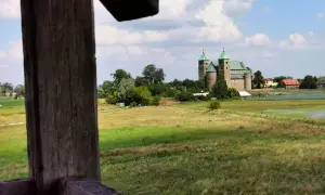 Wnętrze kolegiaty z rzędami drewnianych ławek i witrażami w oknach.