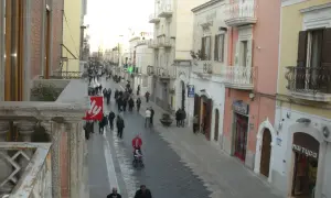Passeggiata serale per gli abitanti di Manfredonia in una via commerciale animata, con negozi e palazzi storici.