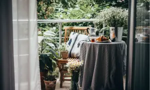 Gemütlich einen kleinen Balkon gestalten: Frühstück mit Kaffee, Croissant und Blumen auf dem Tisch.