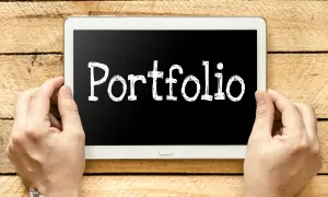 Ręce trzymają tablet z napisem "Portfolio". Szukasz e-portfolio przykłady?