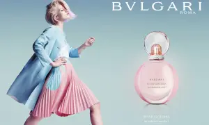 Kobieta w pastelowej stylizacji obok flakonu perfum Bvlgari Rose Goldea Blossom Delight.