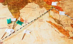 Eine Weltkarte mit Stecknadeln und einer Schnur, die eine Route markiert. Eine Mini-Weltreise beginnt in Indien und führt über die Malediven und Sri Lanka nach Südostasien.
