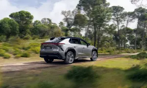 Srebrny Toyota bz4x cena jest atrakcyjna, gdy jedzie po leśnej drodze.