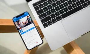 Chcesz wiedzieć, jak sprawdzić na jakich urządzeniach jesteś zalogowany na FB? Na ekranie telefonu widać stronę Facebooka, obok klawiatura laptopa.