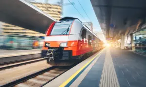 Nowoczesny, czerwono-biały pociąg ekspresowy na nowoczesnym dworcu kolejowym, w ruchu.