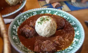 Herzhaftes Gulasch mit Klößen, ein klassisches Gulasch Rezept, serviert auf einem Teller mit grünem Muster.