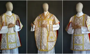 Elegancka wierzchnia szata liturgiczna z białego jedwabiu ze złotym haftem i czerwonym podszyciem.