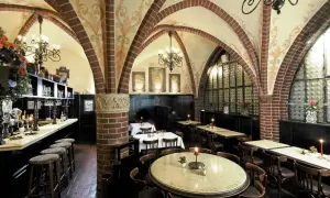 Gemütliche Atmosphäre in einem Berliner Restaurant mit Gewölbedecke, Kronleuchtern und Holztischen.
