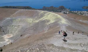 Une randonnée en Sicile sur un volcan actif, avec des sentiers rocailleux et une vue sur la mer et un village.