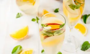 Verre de sangria blanche garni de tranches de pomme, d'orange et de menthe fraîche. Parfait pour une journée ensoleillée.