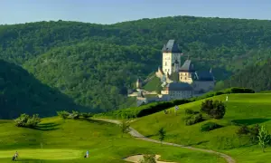 Burg Karlštejn thront majestätisch über einer grünen Golflandschaft.