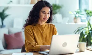 Femme concentrée sur son ordinateur portable, effectuant une recherche sur la naissance d'une personne.