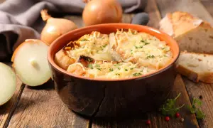 Un bol de soupe à l'oignon gratinée, prêt à être dégusté. Une recette réconfortante avec du pain et du fromage fondu.