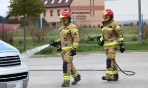 Strażacy w akcji, jeden z węża wodnego. Zastanawiasz się, ile zarabia strażak? To praca pełna poświęcenia.