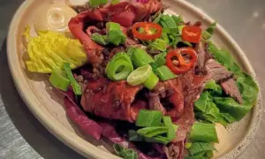 En läcker sallad med marinerad rostbiff, garnerad med salladslök och chili. Serveras med en krämig sås och krispig sallad.