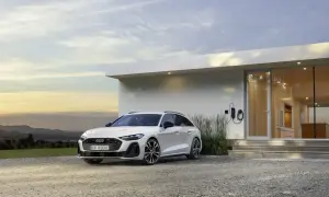 Białe Audi A6 Avant TFSI, zaparkowane przed nowoczesnym domem z ładowarką.