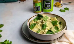Miseczka kremowego curry z kurczakiem i szpinakiem, przygotowanego z zielonej pasty curry i mleczka kokosowego.