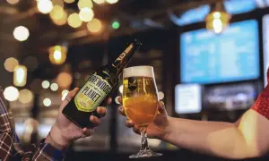 Brindisi con birra BrewDog Planet Pale Ale, perfetta per la Italy Beer Week. Luci soffuse e atmosfera da pub.