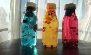 Tres botellas sensoriales caseras llenas de líquido brillante y bolitas de colores.