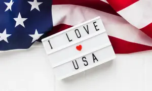 Amerykańska flaga i tablica z napisem "I LOVE USA". Zastanawiasz się, ile kosztuje bilet do USA w dwie strony?