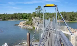 Hängbro över vatten med skogklädda öar. Perfekt för en utflykt Stockholm.