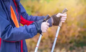 Osoba w kurtce przygotowuje się do marszu, trzymając kijki trekkingowe. Poznaj, jak chodzić z kijkami trekkingowymi, by czerpać z tego maksimum korzyści.