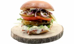 Soczysty burger z jalapeno, pomidorem, cebulą i ogórkiem na drewnianym plastrze.