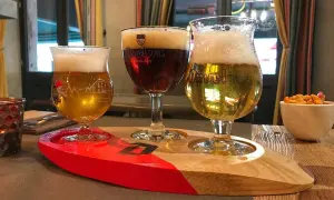 Tre bicchieri di birra su un vassoio di legno, pronti per essere gustati al tavolo.