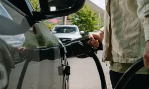 Persona che collega il cavo di ricarica a un'auto elettrica, un'azione che influisce sul costo ricarica auto elettrica.