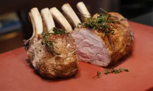 Ein saftiger Semerrolle Kalb Braten, mit Kräutern garniert, liegt auf einem roten Schneidebrett.