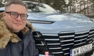 Mężczyzna w okularach i futrzanej kurtce pozuje do selfie przed jasnoniebieskim Jetour Dashing na tle zimowego lasu.