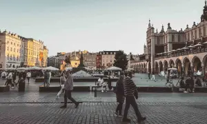 En livlig torgscen i Krakow, perfekt för din reseguide. Människor promenerar förbi historiska byggnader och marknadsstånd.