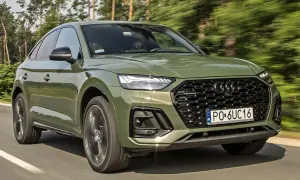 Zielony Audi Q5 Sportback w ruchu. Kierowca w okularach przeciwsłonecznych. Wiele pozytywnych audi q5 opinie o tym modelu.