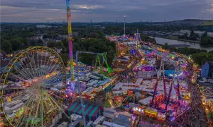 Buntes Lichtermeer auf Volksfesten im Herbst: Riesenrad, Hochbahn und Fahrgeschäfte beleuchten die Nacht.