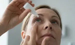 Kobieta wykonuje zakraplanie oczu, aplikując kroplę leku.
