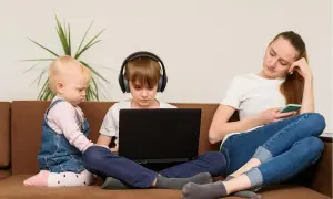 Matka z telefonem, syn w słuchawkach przy laptopie, młodsze dziecko obok. Jak rozmawiać z nastolatkiem, gdy wszyscy są w swoich światach?