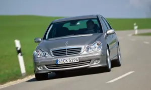 Srebrny Mercedes W203 1.8 Kompressor z kierowcą za kierownicą jedzie po krętej drodze wśród zielonych wzgórz.